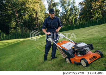 With lawn mover, working. Professional gardener is on the lawn 133615088