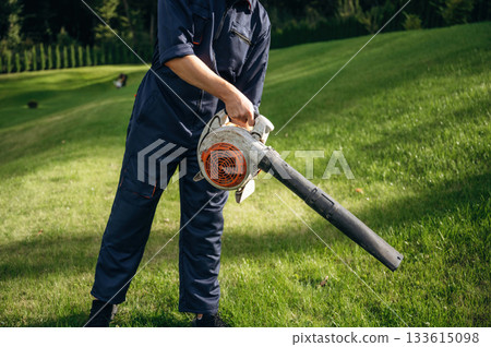 Working by using leaf blower. Professional gardener is on the lawn Working by using leaf blower. Professional gardener is on the lawn 133615098