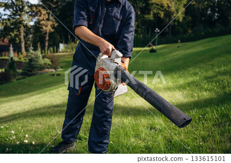 Working by using leaf blower. Professional gardener is on the lawn Working by using leaf blower. Professional gardener is on the lawn 133615101