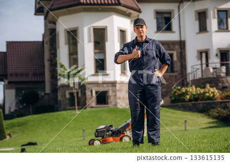 Job well done, finished cutting the grass with lawn mover. Professional gardener is on the lawn 133615135