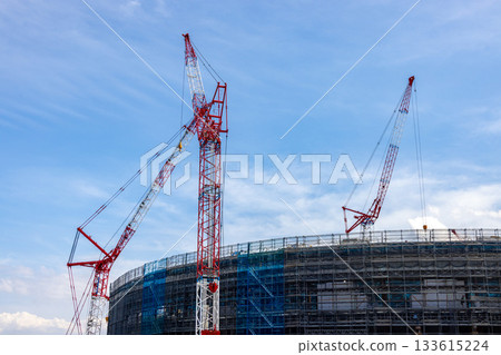 在湛藍的天空下,三台起重機正在體育場建築工地忙碌作業。 在湛藍的天空下,三台起重機正在體育場建築工地忙碌作業。 133615224