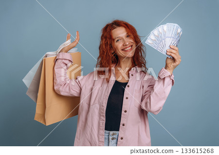 Ready to spend some cash for shopping. Woman is in the studio against background Ready to spend some cash for shopping. Woman is in the studio against background 133615268