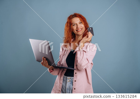Conception of online shopping, with credit card and laptop. Woman is in the studio against background 133615284