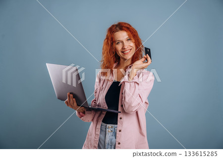 Conception of online shopping, with credit card and laptop. Woman is in the studio against background 133615285
