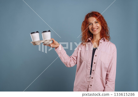 Cups of coffee, hot drink. Woman is in the studio against background 133615286