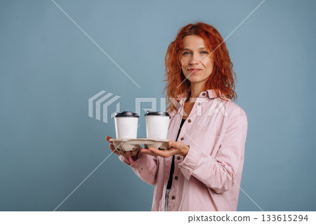 White cups of drinks, holding it. Woman is in the studio against background White cups of drinks, holding it. Woman is in the studio against background 133615294