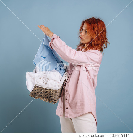 Taking a look at washed clothes. Woman is in the studio against background 133615315
