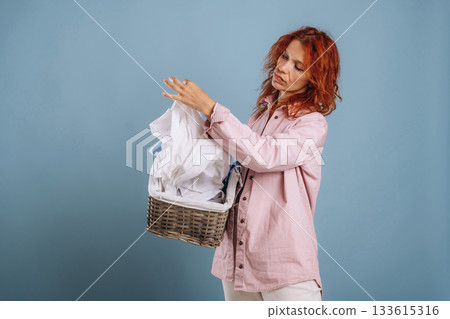 Taking a look at washed clothes. Woman is in the studio against background Taking a look at washed clothes. Woman is in the studio against background 133615316