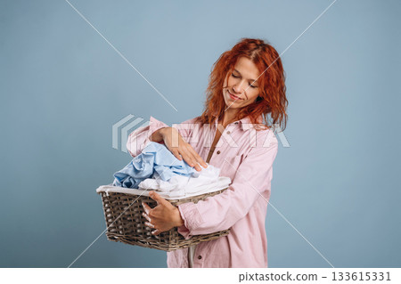 Taking a look at washed clothes. Woman is in the studio against background 133615331
