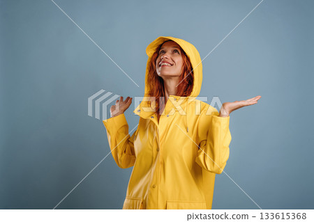 Looking for a rain, in yellow coat. Woman is in the studio against background 133615368
