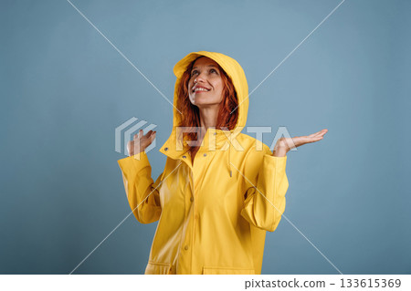 Looking for a rain, in yellow coat. Woman is in the studio against background 133615369
