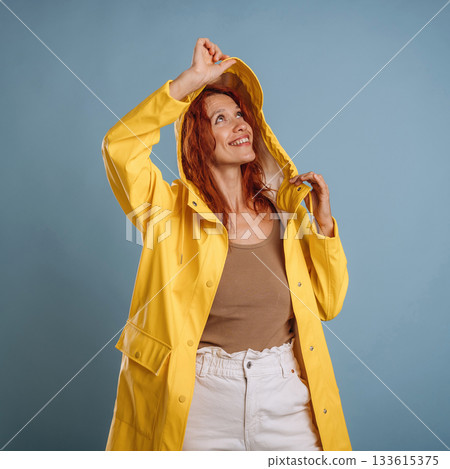 Ready for the rain, in yellow coat. Woman is in the studio against background Ready for the rain, in yellow coat. Woman is in the studio against background 133615375