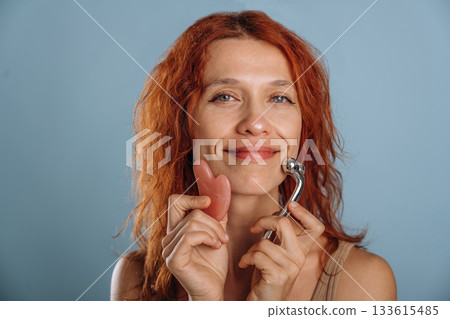 Patch and massager are used on the face. Woman is in the studio against background 133615485