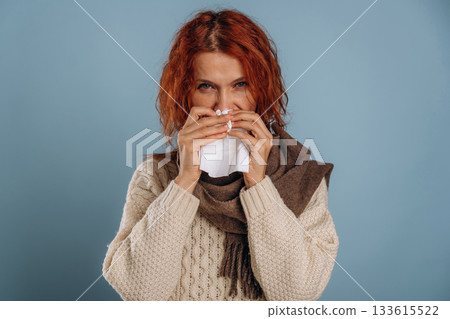 In scarf and with napkins, feeling sick. Woman is in the studio against background 133615522