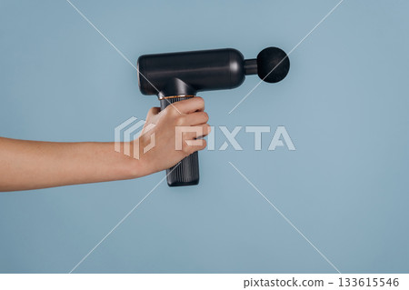 Female hand is holding electric massager against blue background Female hand is holding electric massager against blue background 133615546