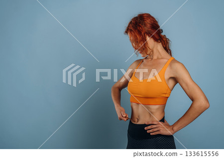 In yellow top, sportive clothes. Woman is in the studio against background In yellow top, sportive clothes. Woman is in the studio against background 133615556