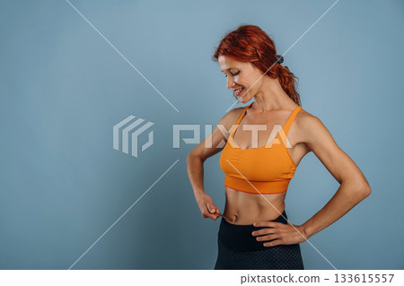In yellow top, sportive clothes. Woman is in the studio against background In yellow top, sportive clothes. Woman is in the studio against background 133615557