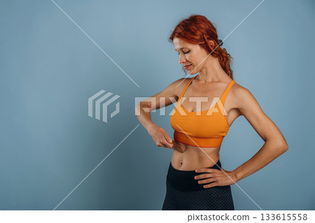 Woman in sportive clothes is in the studio against background 133615558