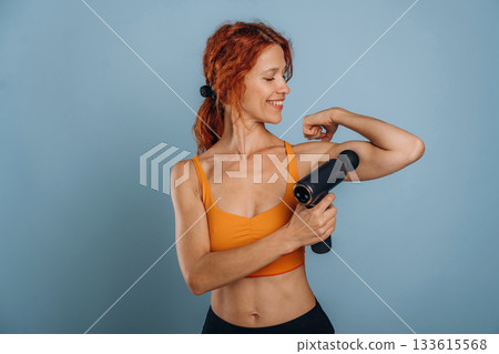 Fitness, sport conception. With automatic massager. Woman is in the studio against background Fitness, sport conception. With automatic massager. Woman is in the studio against background 133615568