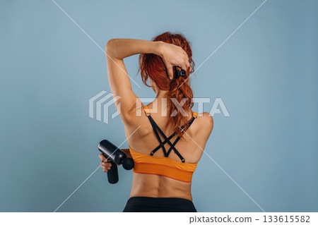 Professional electric automatic massager. Woman is in the studio against background 133615582