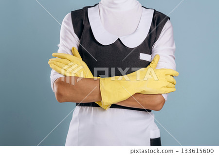 Hands in yellow gloves, maid is ready for work. Woman is in the studio against background 133615600