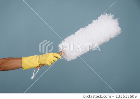 Maid is holding dust brush against blue background 133615609