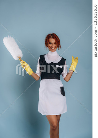Maid is with dust brush. Woman is in the studio against background 133615610