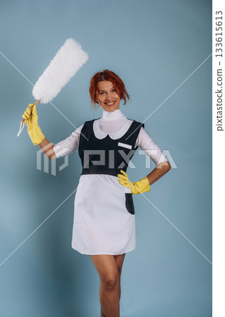 Maid is with dust brush. Woman is in the studio against background 133615613