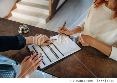 Registration process, document. Woman is at reception of the modern hotel 133615849