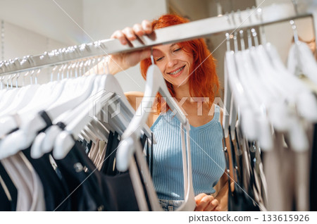 Redhead woman chooses clothes in retail store Redhead woman chooses clothes in retail store 133615926