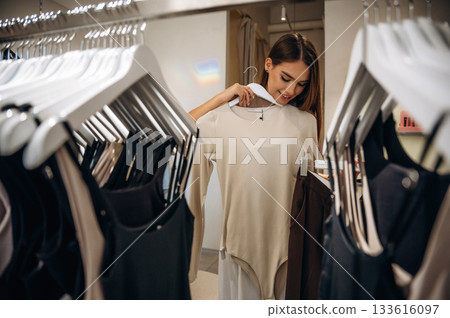 Feeling joy, cheerful. Woman chooses clothes in retail store 133616097