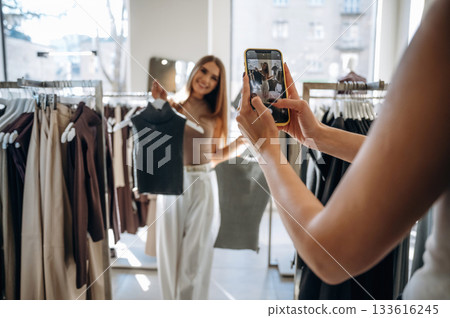 Two female friends are in the retail store, choosing clothes, shopping 133616245