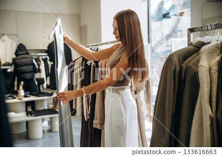 Handlers with bunch of wear. Woman chooses clothes in retail store 133616663