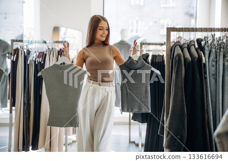 Making the choice. Woman chooses clothes in retail store Making the choice. Woman chooses clothes in retail store 133616694