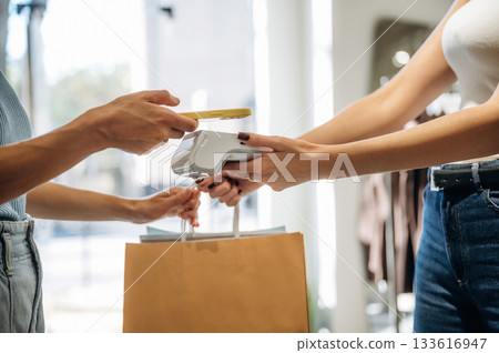Wireless payment. Woman is paying for clothes, in the retail store 133616947