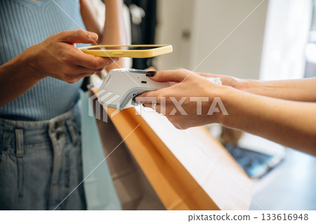 Wireless payment. Woman is paying for clothes, in the retail store Wireless payment. Woman is paying for clothes, in the retail store 133616948