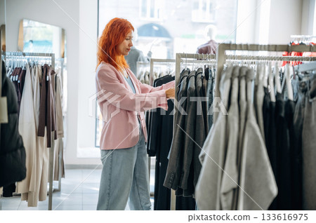 Customer is looking for new wear. Woman chooses clothes in retail store Customer is looking for new wear. Woman chooses clothes in retail store 133616975