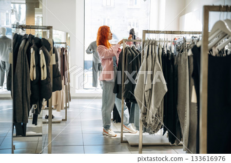 Customer is looking for new wear. Woman chooses clothes in retail store Customer is looking for new wear. Woman chooses clothes in retail store 133616976