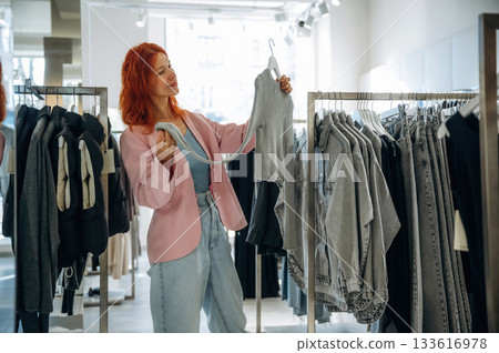 Customer is looking for new wear. Woman chooses clothes in retail store 133616978