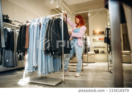 Customer is looking for new wear. Woman chooses clothes in retail store 133616979