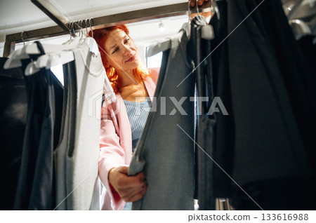 Bunch of wear on the handlings. Woman chooses clothes in retail store Bunch of wear on the handlings. Woman chooses clothes in retail store 133616988