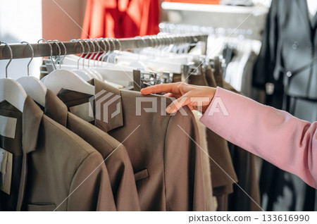 Touching the wear. Close up view of woman that is chooses clothes in the retail shop Touching the wear. Close up view of woman that is chooses clothes in the retail shop 133616990