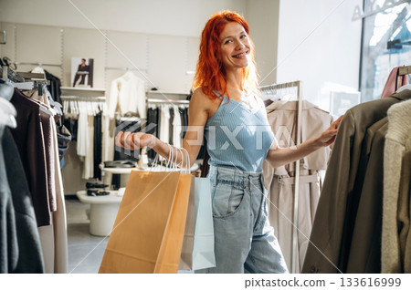 Under sunlight, bunch of wear. Woman chooses clothes in retail store Under sunlight, bunch of wear. Woman chooses clothes in retail store 133616999