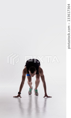 Runner in crouched forward position preparing to sprint 133617364