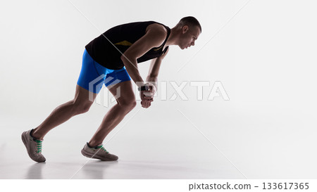 Runner bending forward and checking smartwatch after effort. 133617365