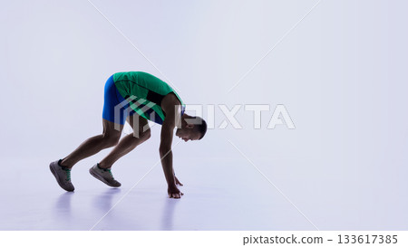 Runner leaning deeply forward in explosive launch step Runner leaning deeply forward in explosive launch step 133617385