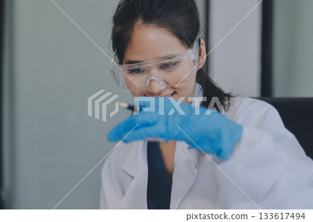 Portrait, science and happy woman on laptop in lab to research chemistry, test or innovation. Microscope, scientist and face of medical doctor in goggles for microbiology, healthcare or pharma study 133617494