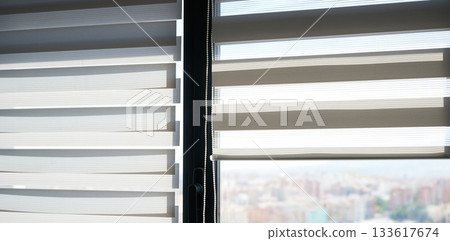 Modern zebra window blinds with soft daylight filtering through layered fabric panels in a bright interior 133617674