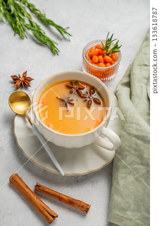 Sea buckthorn herbal tea in a cup on a light background with spices, herb and berries. Sea buckthorn herbal tea in a cup on a light background with spices, herb and berries. 133618787