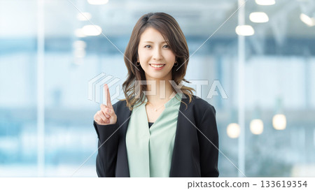 A smiling woman pointing with her index finger up 133619354